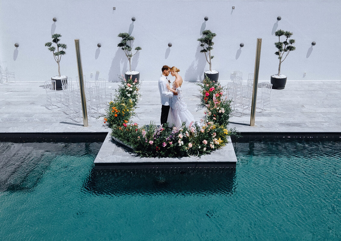 Luxury wedding venue in Mykonos featuring romantic poolside ceremony with colorful floral arrangements