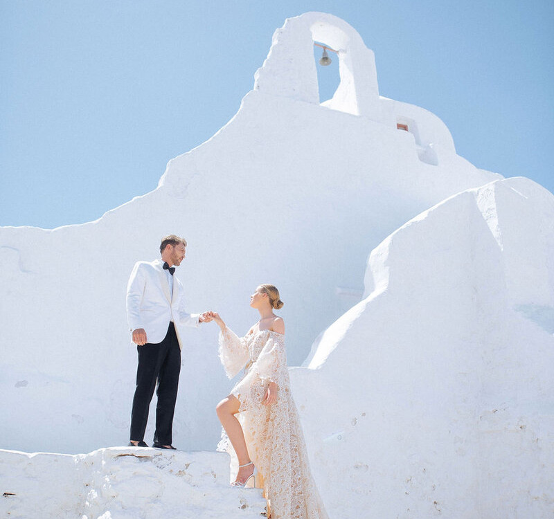 Luxury Greek island wedding in Mykonos — elegant couple at white chapel for dream destination wedding in Greece.