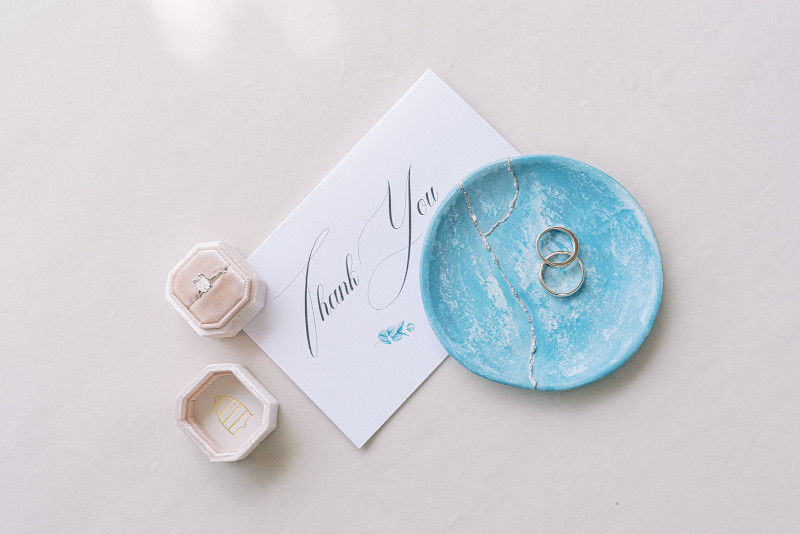 A wedding ring and a thank note placed on a blue plate, symbolizing the union of two hearts in a Mykonos wedding ceremony.